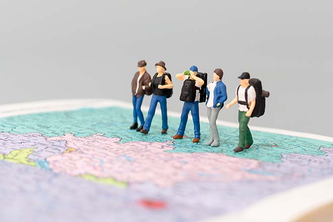Figuras de personas viajeras andando sobre un mapa
