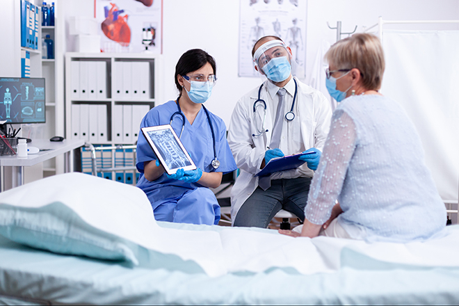 Médico y médica con paciente en centro sanitario