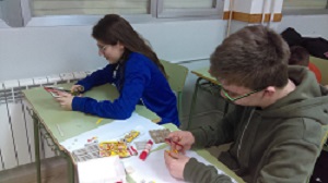 Dos alumnos hacen una manualidad con papel y pegamento.