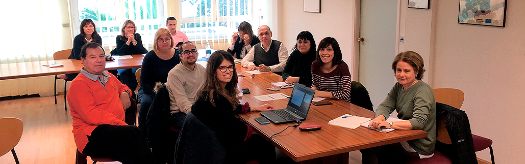 Retrato de varias personas reunidas en torno a una mesa de conferencias, mirando a la cámara